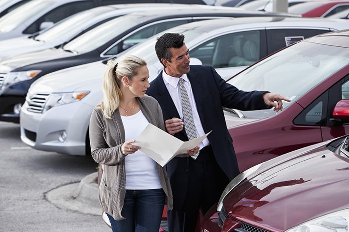 Woman shopping for a new car, talking to a car salesman.