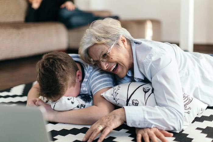 Grandmother and grandchild are sitting behind the laptop an