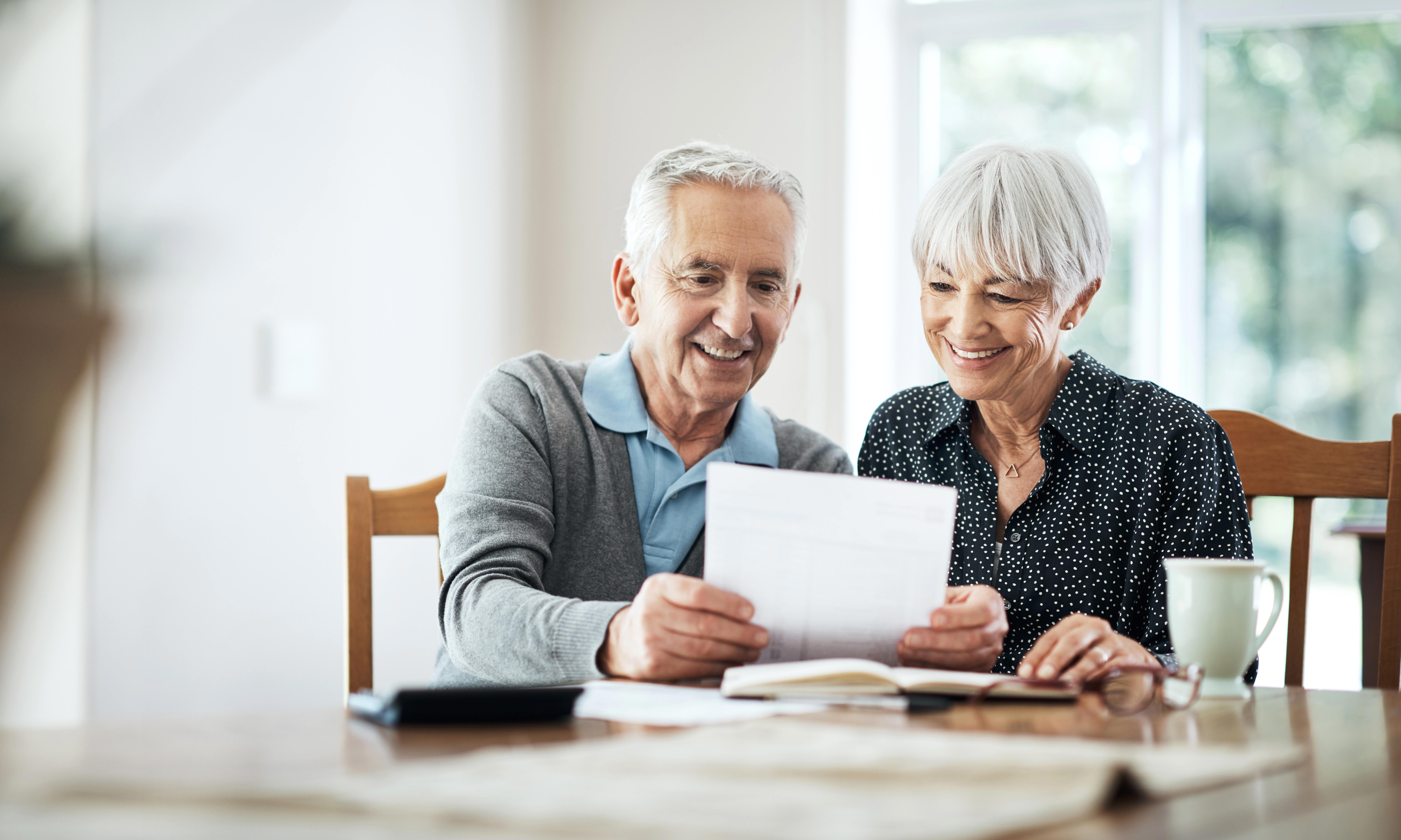 Older couple sitting at dining table reviewing financial documents