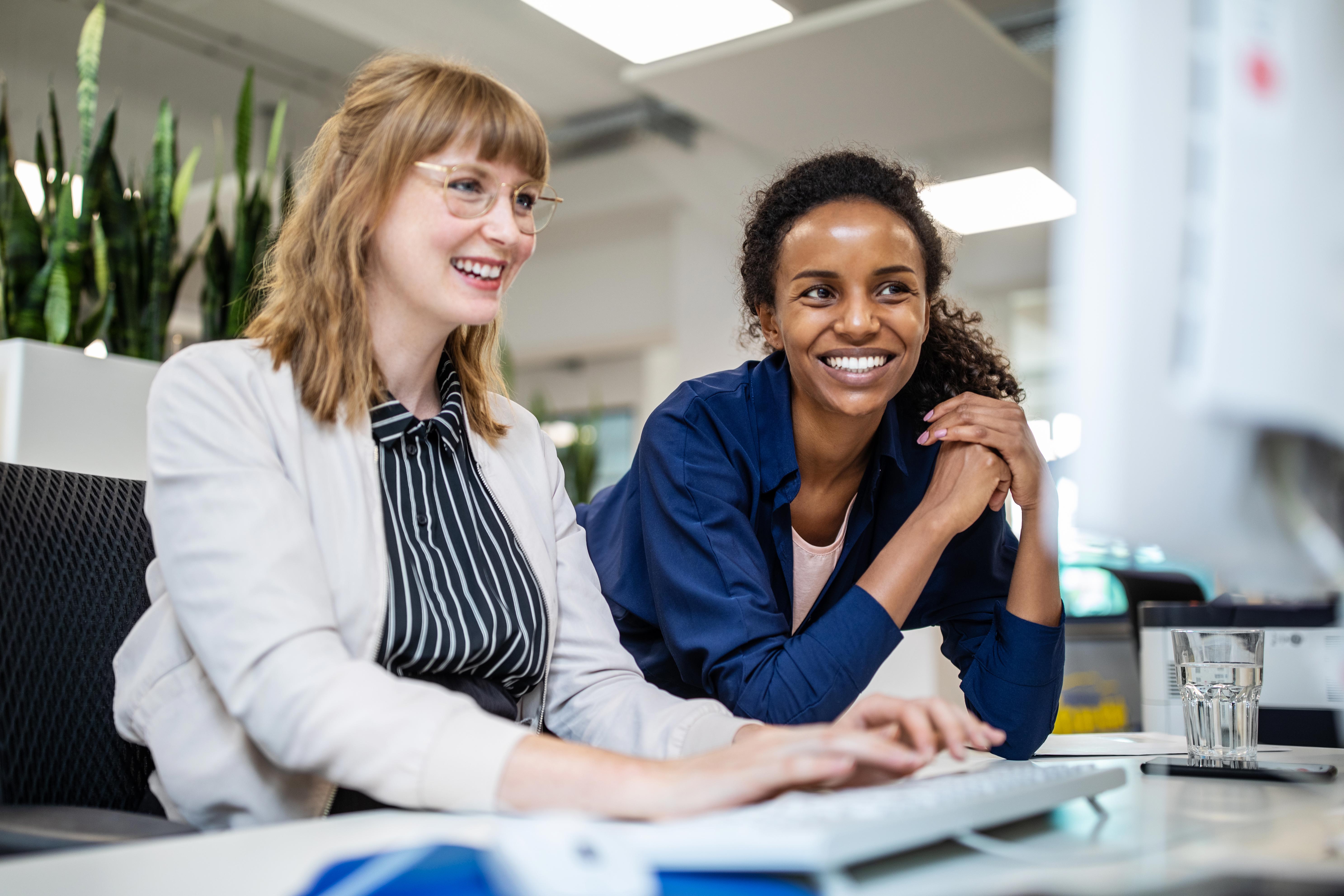 Two women looking at a computer screen while one types