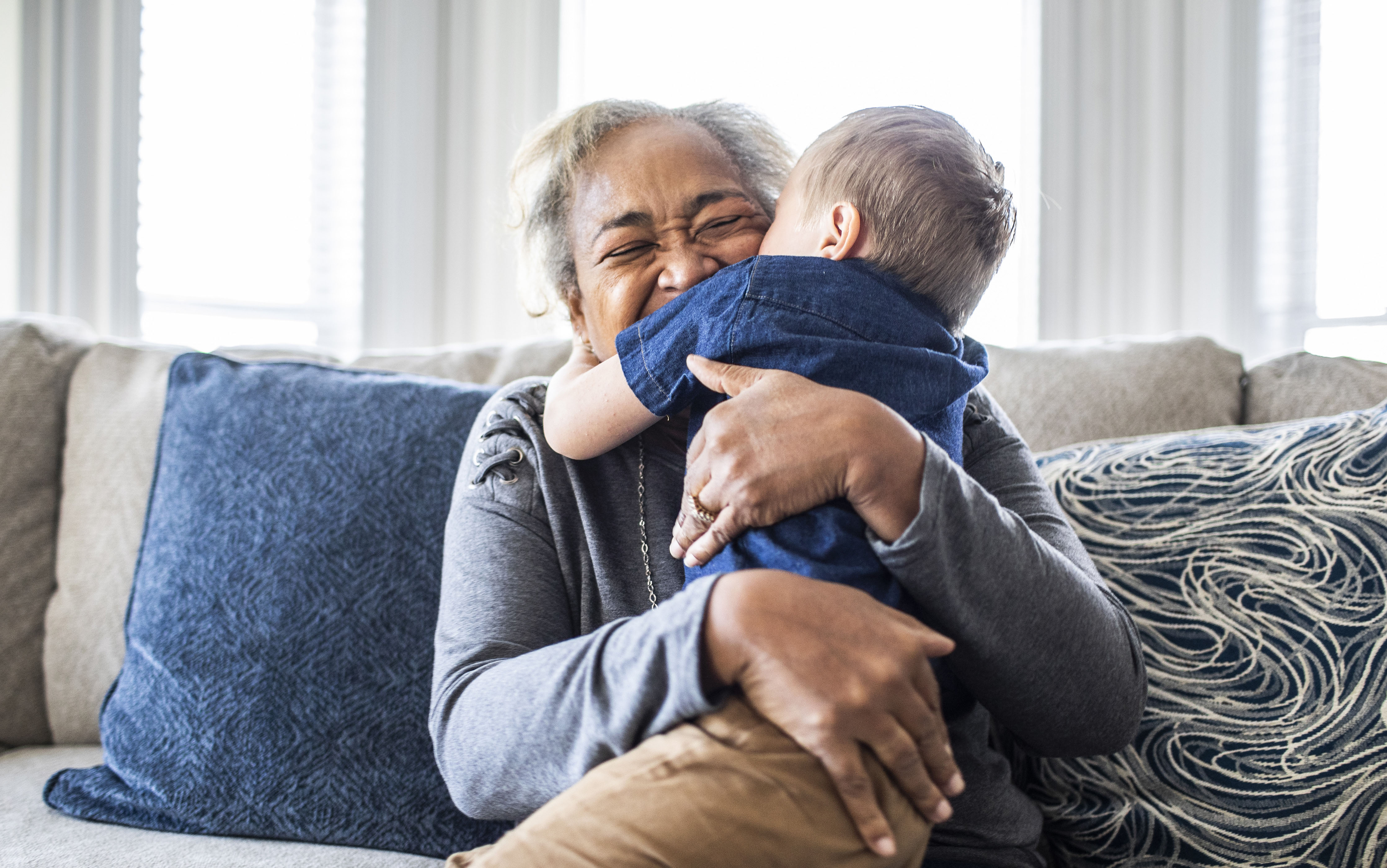 Grandmother embracing toddler grandson and laughing