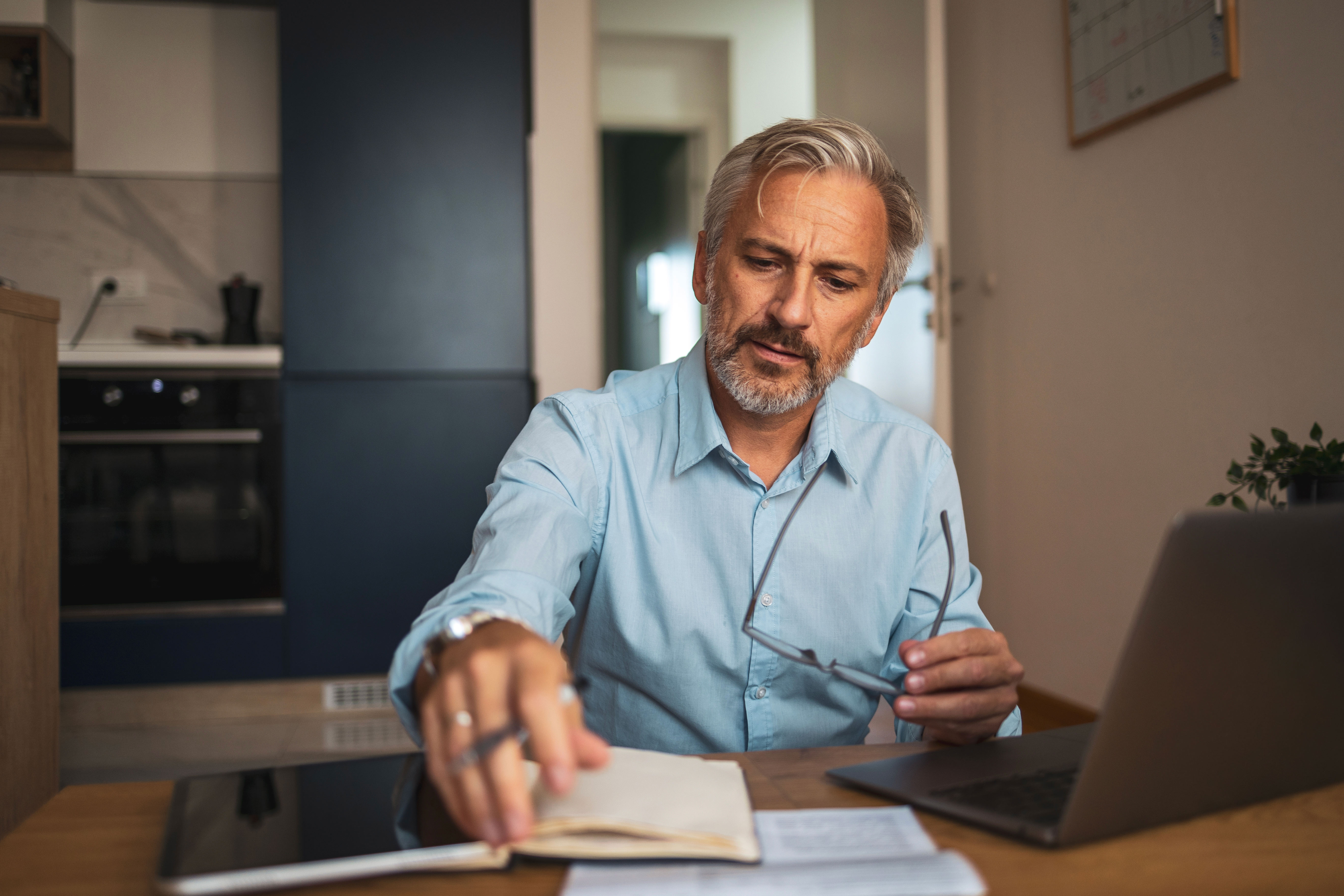 Man at table opening a notebook.