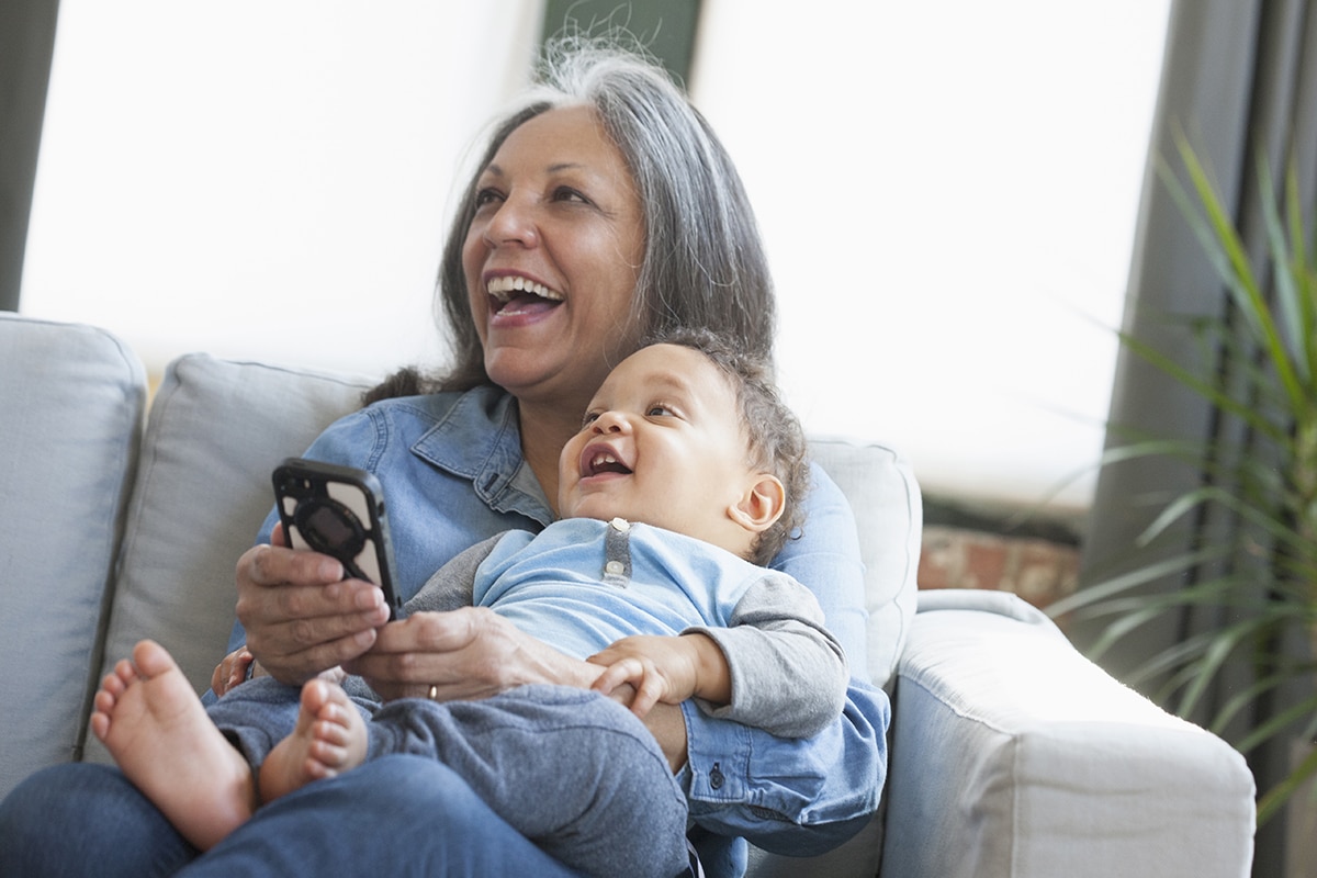 Hispanic grandmother holding grandson and cell phone