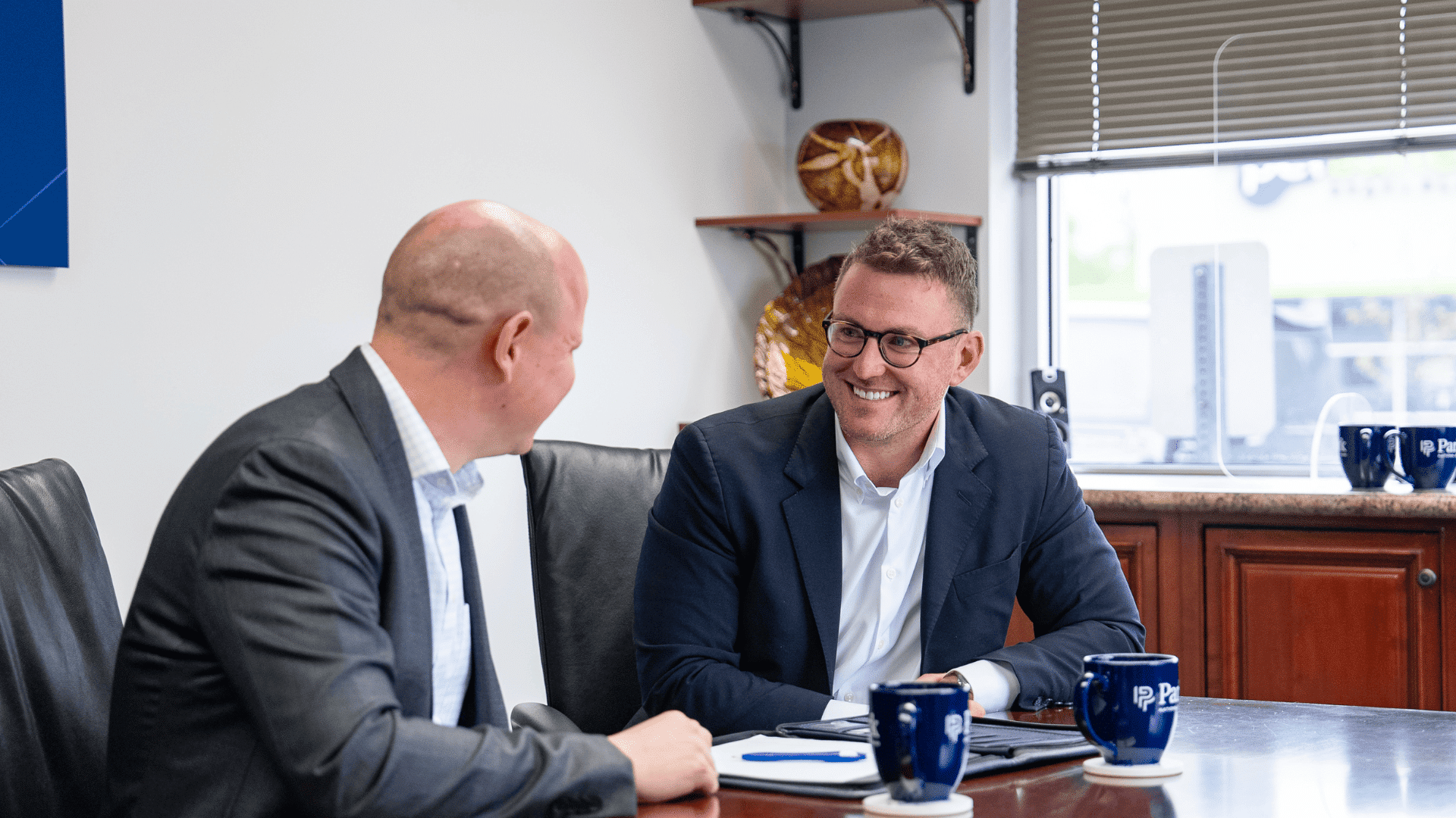 Two professionals sitting at a table and talking.
