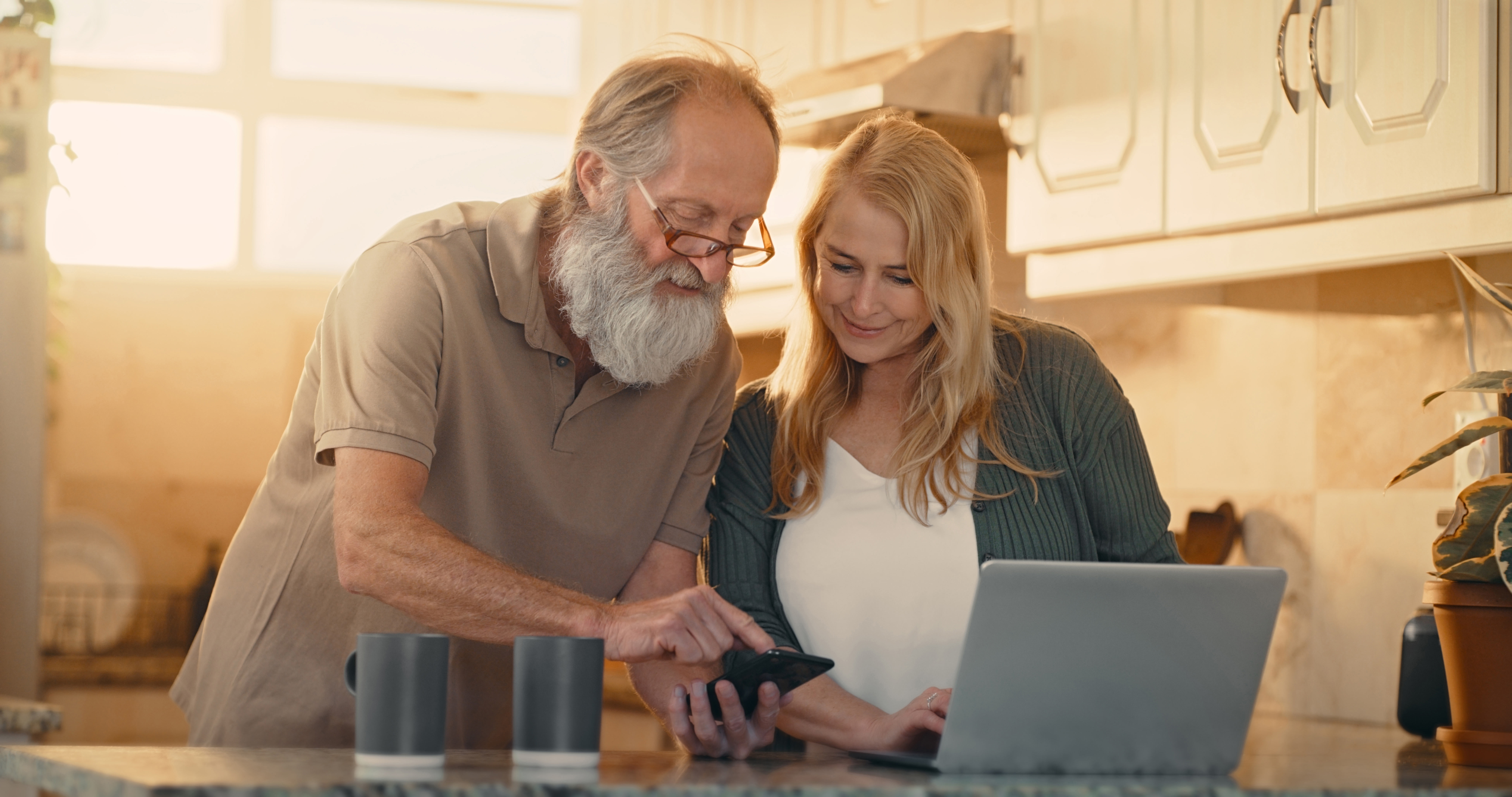 Older couple standing at kitchen island looking at laptop as they plan for the future.