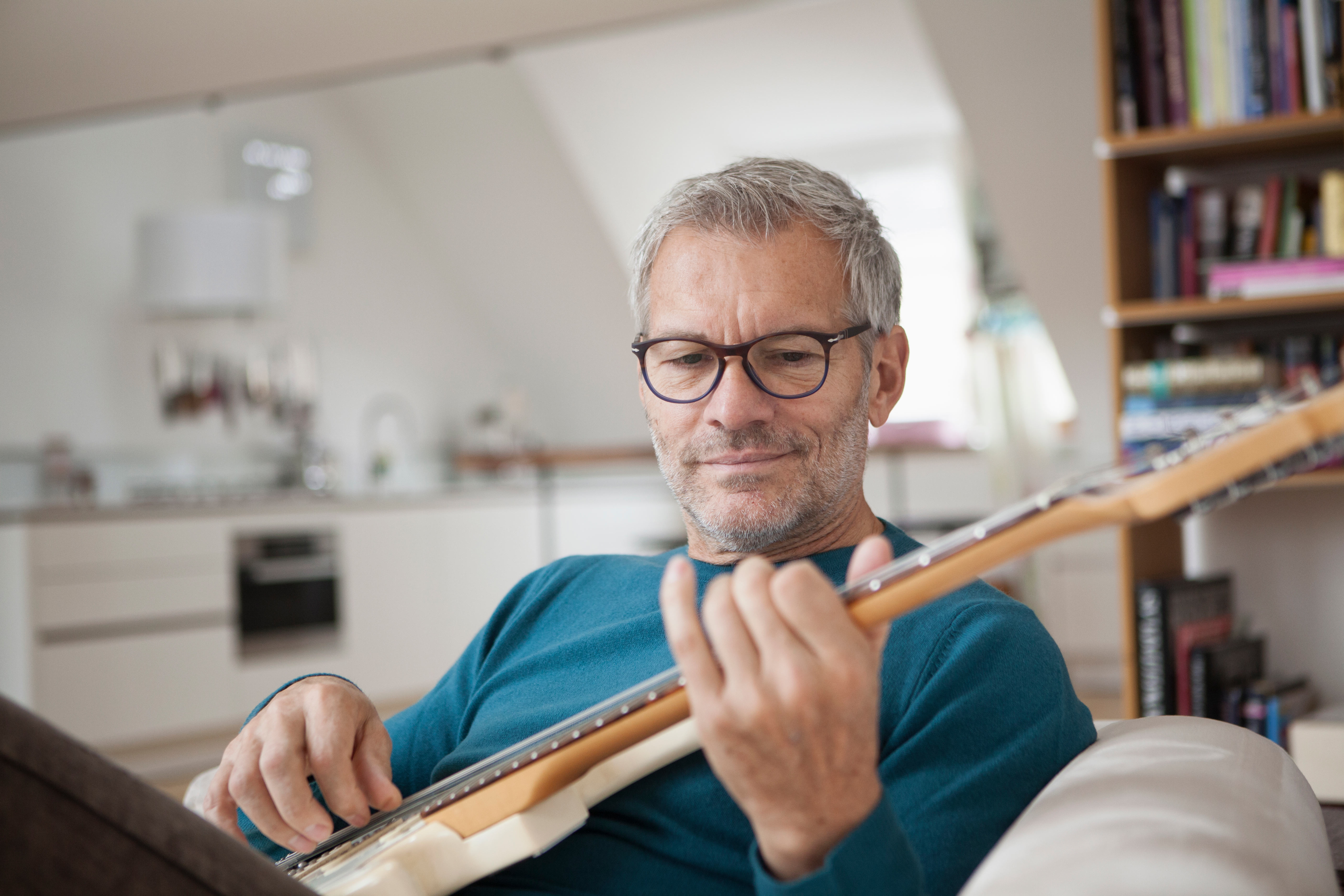 Man sitting on couch playing guitar