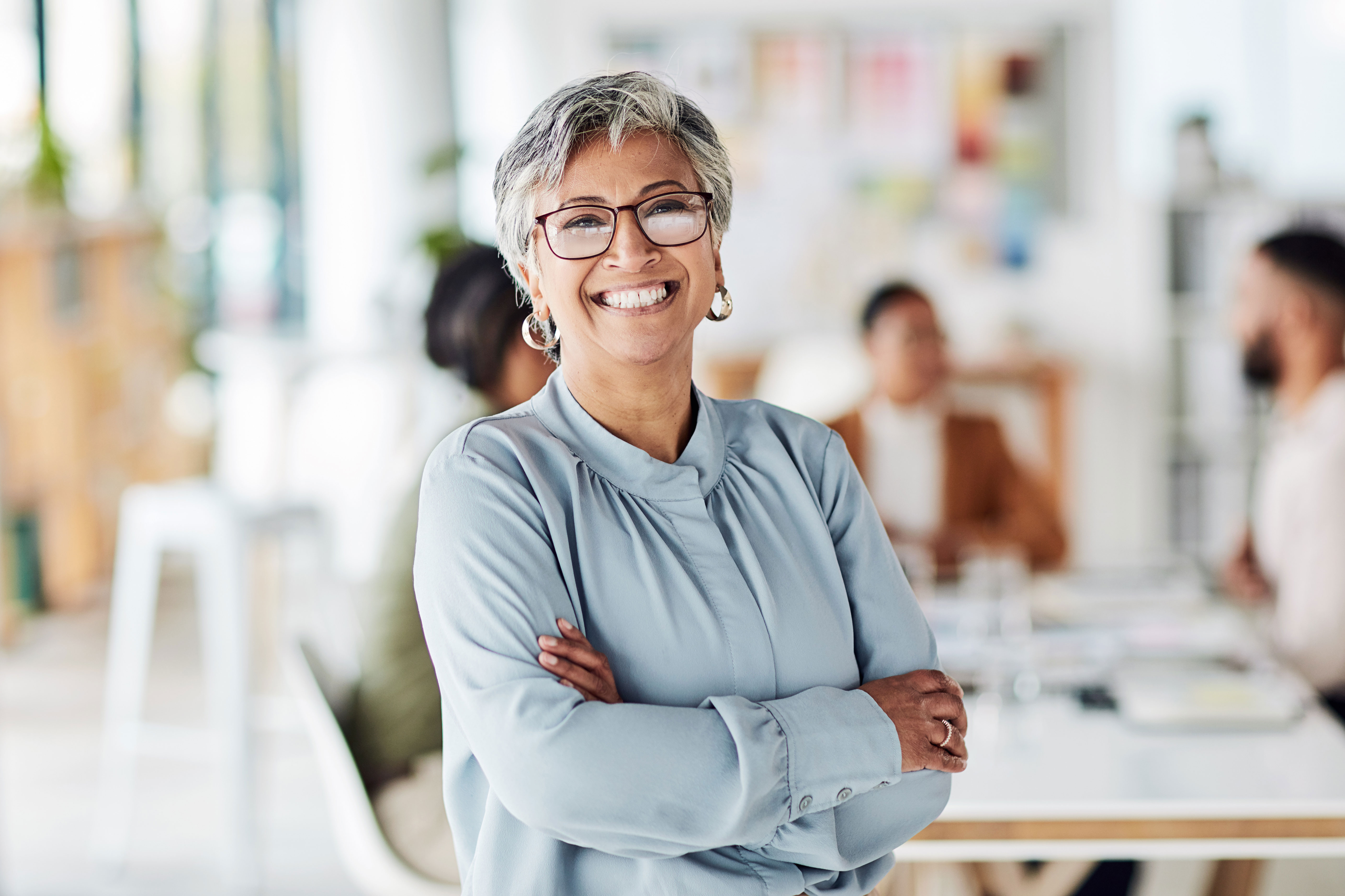 Older working woman standing with arms crossed smiling