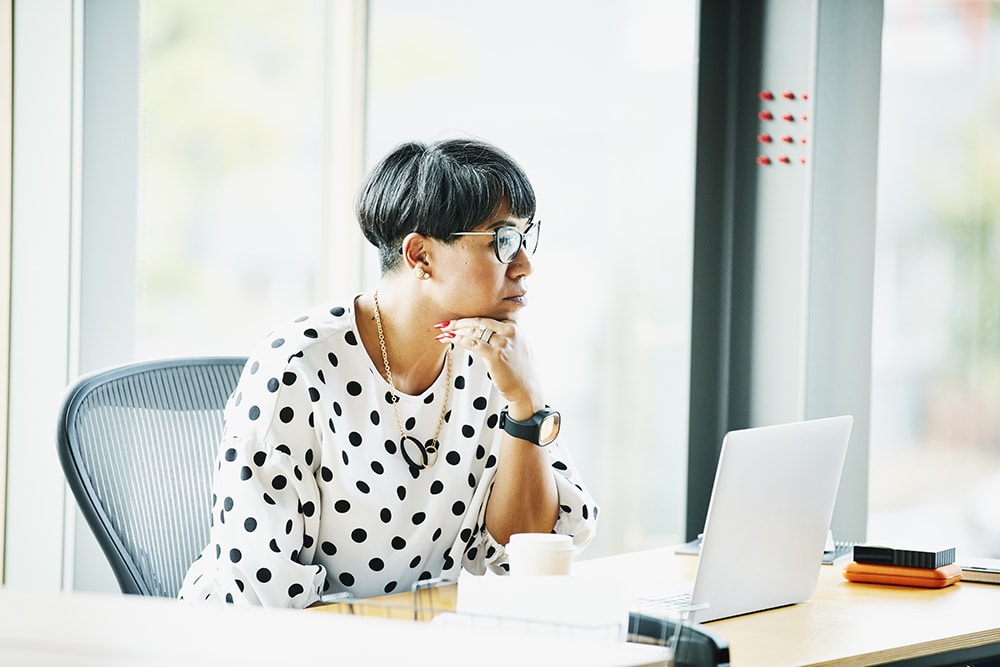 Mature businesswoman working on laptop at workstation in office