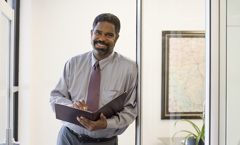 Mature businessman standing in doorway in office, holding file, portrait