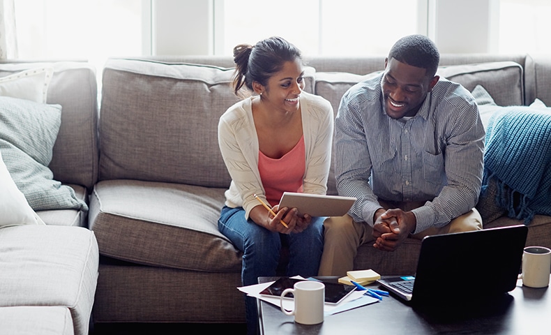 Shot of a young couple going through paperwork together on the sofa at home