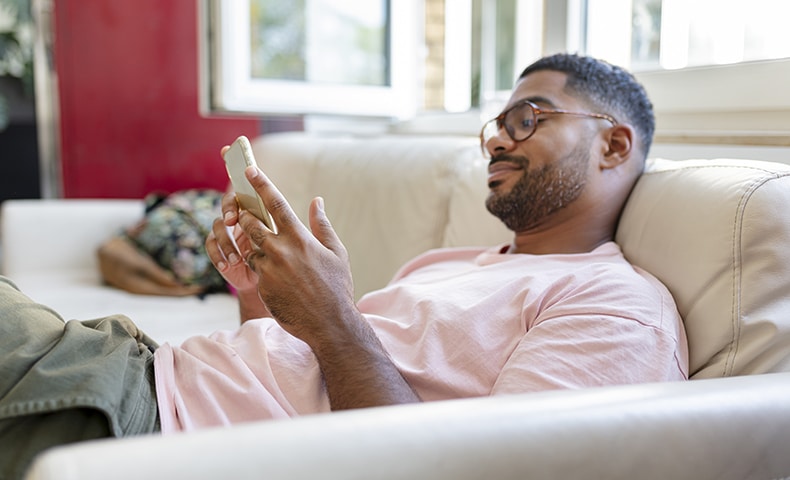 Relaxed man sitting on sofa using cell phone