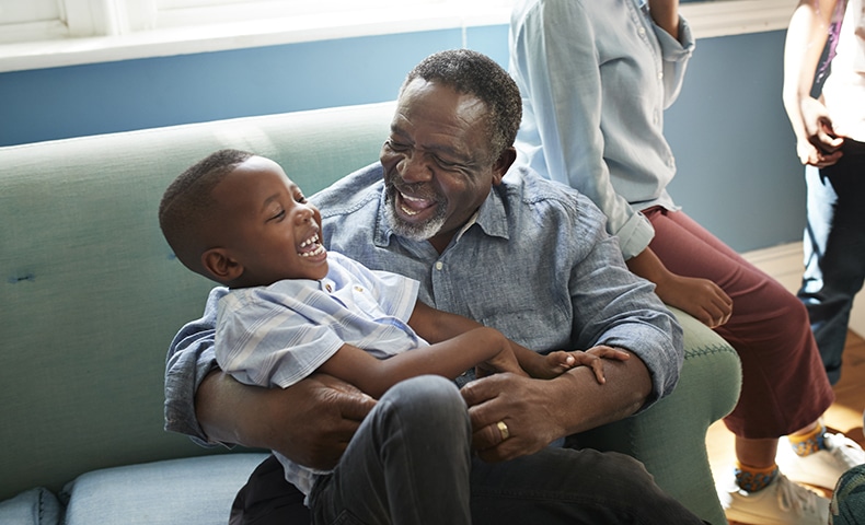 High angle view of happy man playing with boy while sitting on sofa at home