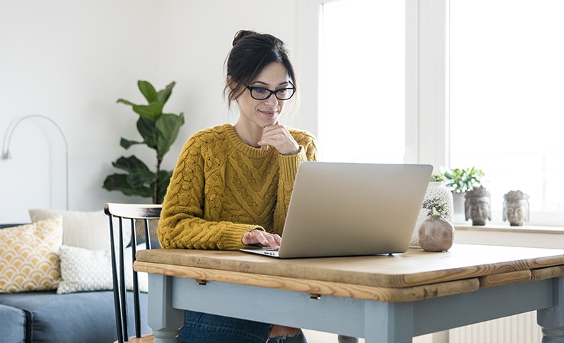 Woman sitting at table, using laptop